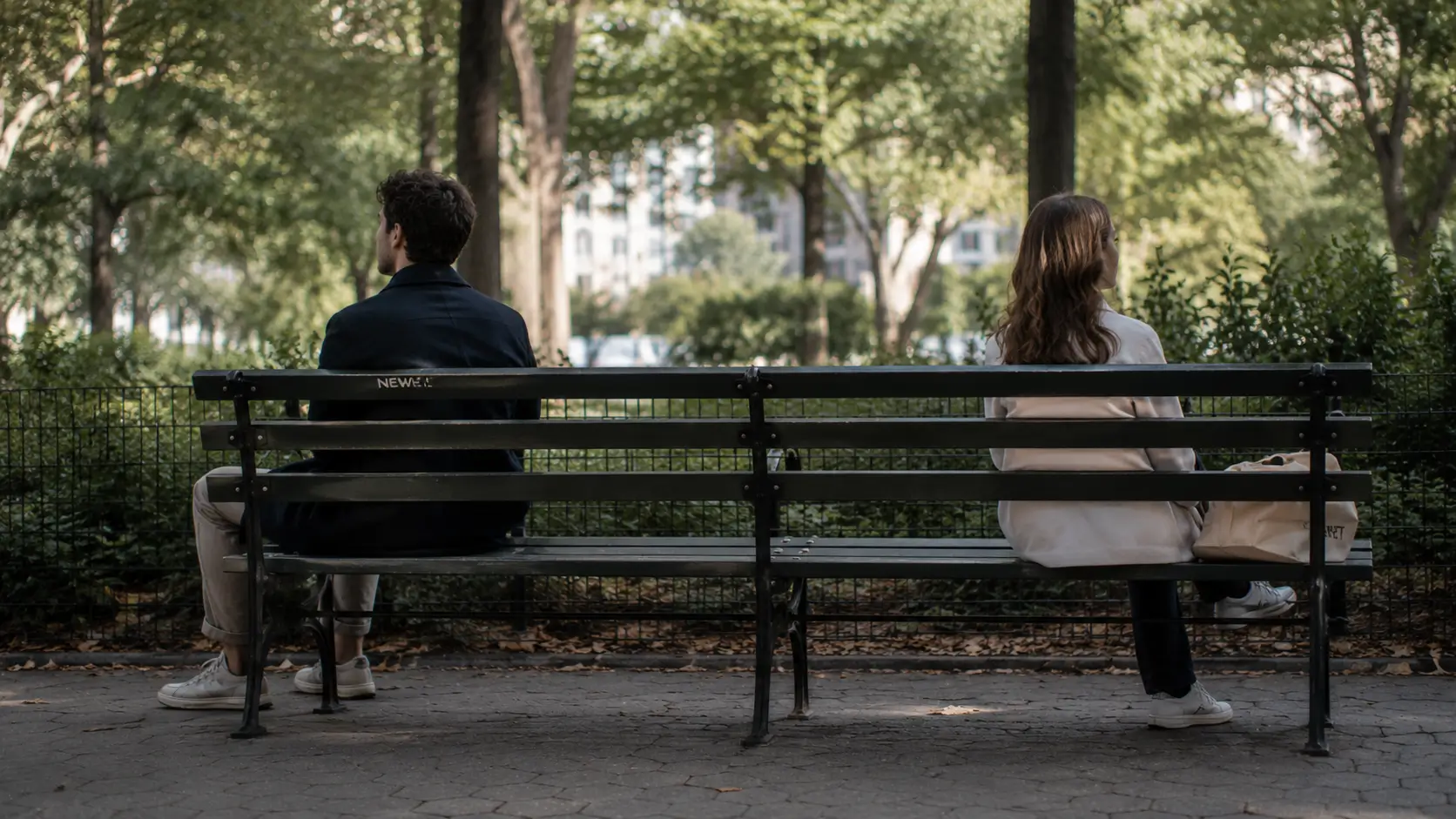 birth chart relationship compatibility — two people sitting on a park bench with space between them, both looking ahead, not at each other, soft daylight