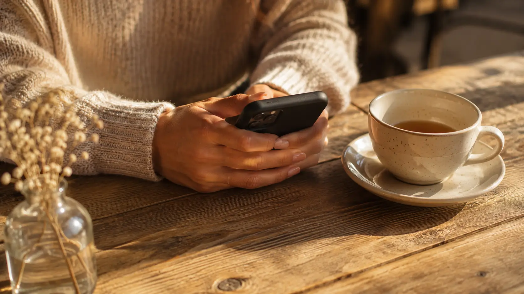 Dating a pisces man — close-up of a woman's hands resting near a phone on a café table, a soft smile implied