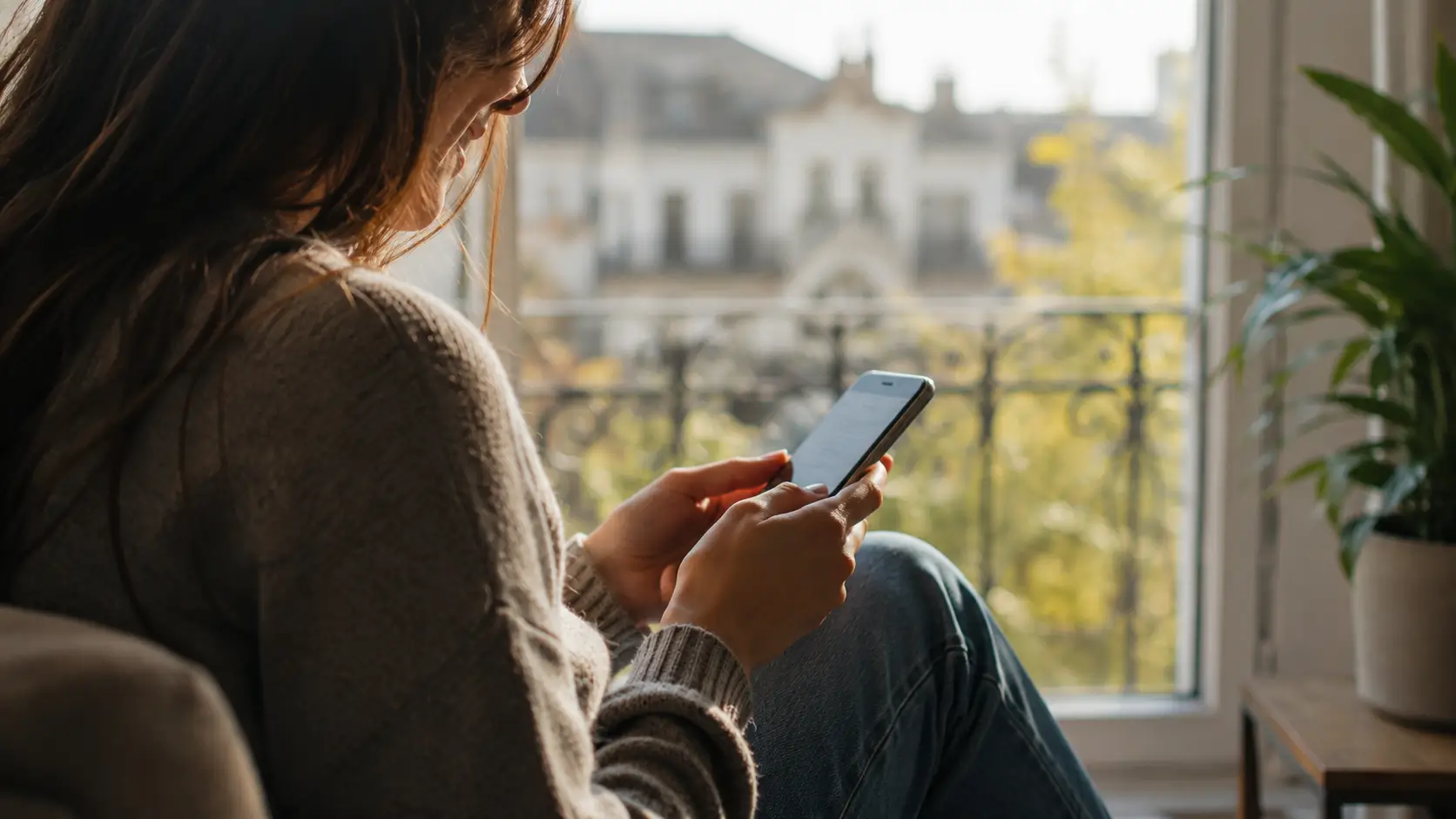Dating a leo man — woman smiling softly while reading a message on her phone, soft natural light