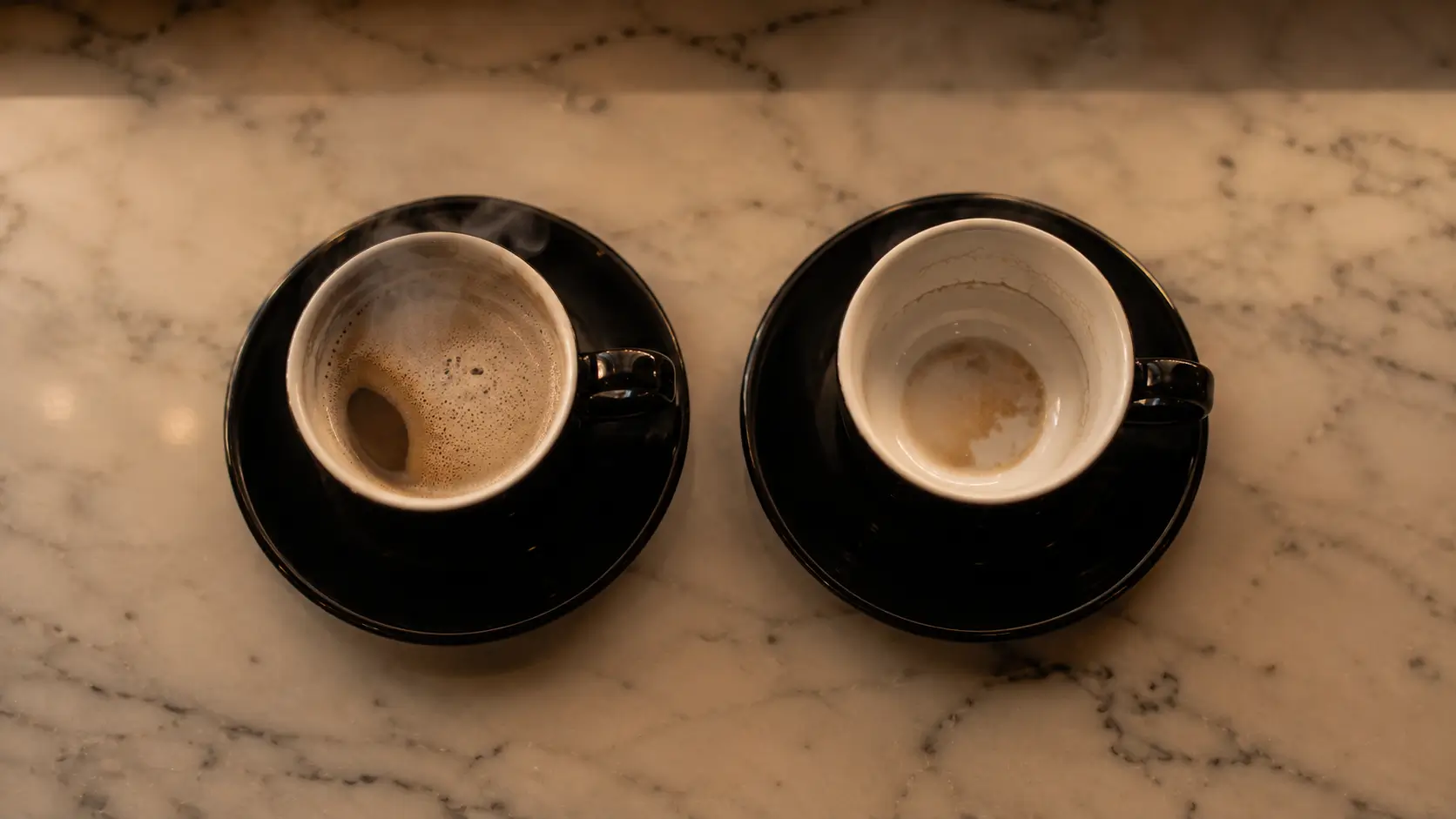 Gemini woman irresistible traits — two identical coffee cups side by side, one full and steaming one cold and empty, marble surface, the visual duality of two natures
