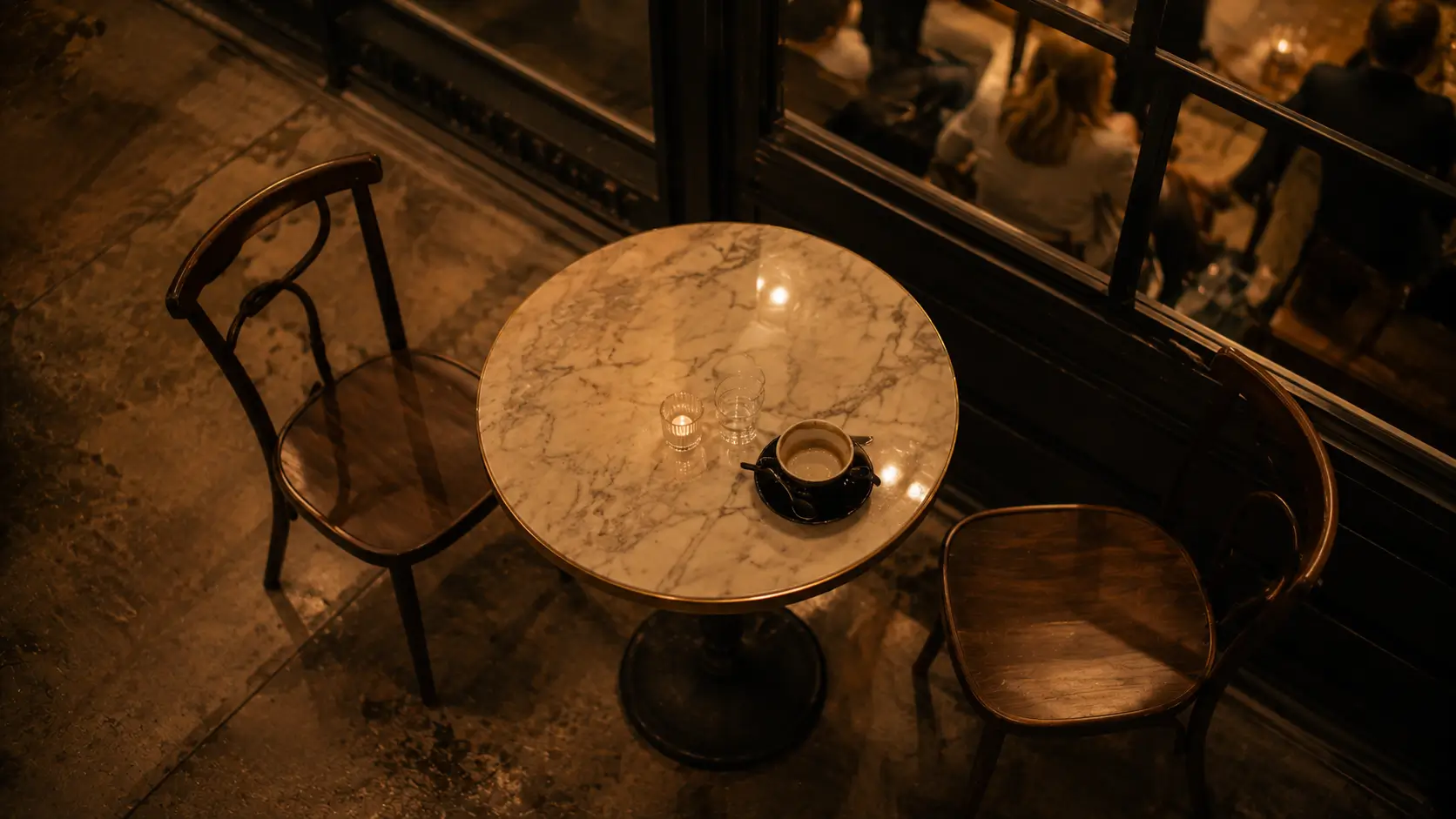 Getting over a gemini woman — two chairs at a café table, one empty, half-drunk coffee cup, warm ambient light, the specific loneliness of someone who just left