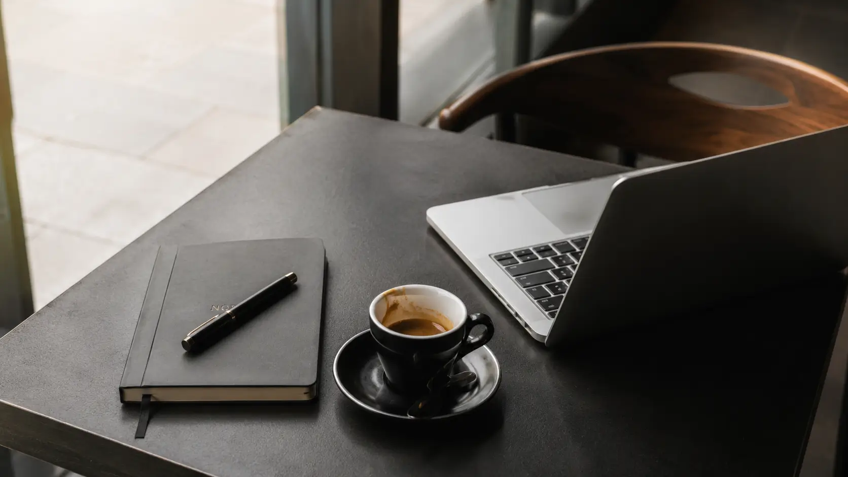Pisces man attracted to capricorn woman — sleek café desk with open laptop, espresso, and notebook, the aesthetic of a woman who came to work and did