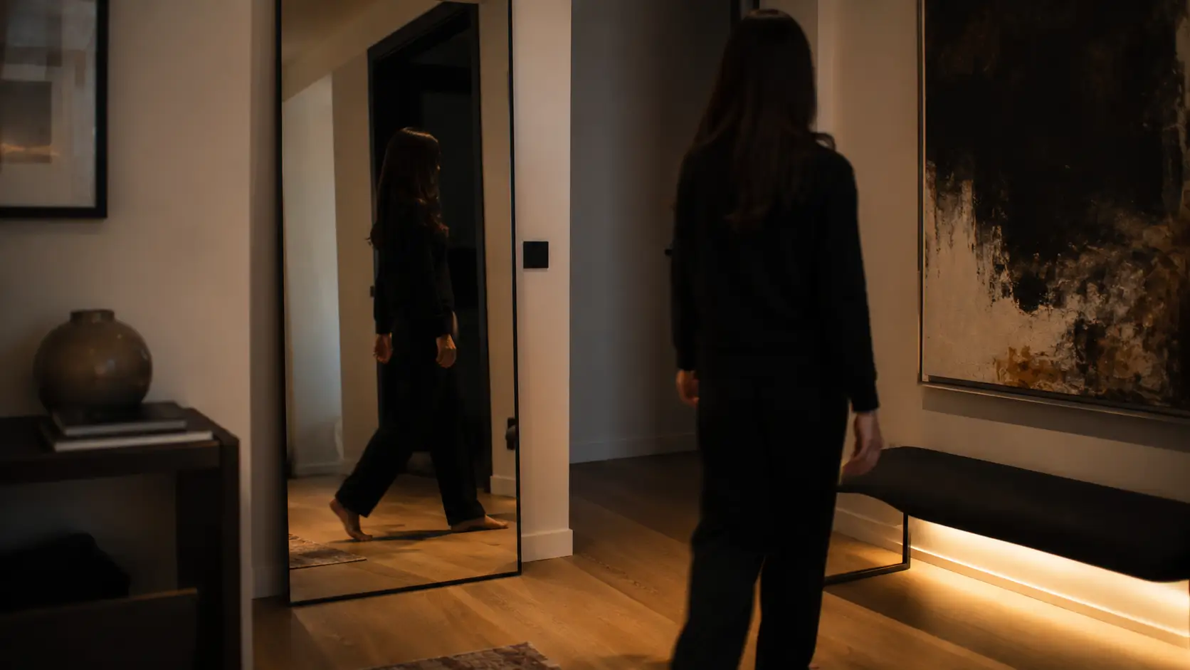Scorpio woman soulmate astrology — woman walking past mirror in apartment hallway, reflection visible