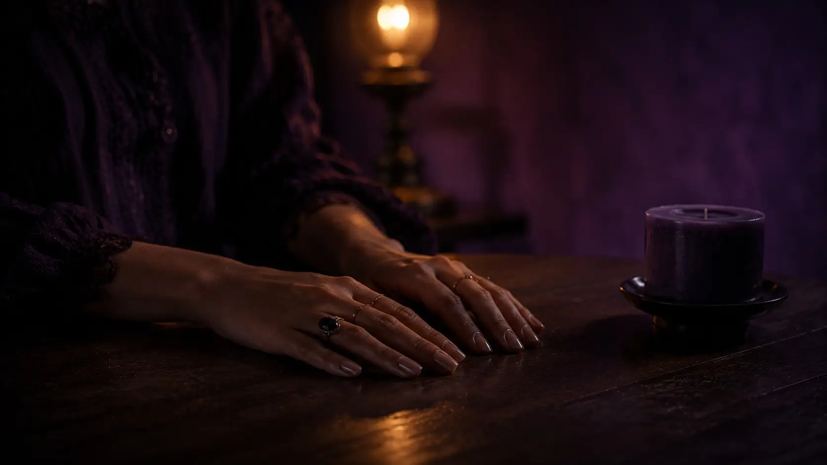 Taurus scorpio attraction — close-up of a woman's hands resting still on a dark table, rings and candlelight, quiet emotional tension